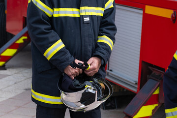 Un pompier en uniforme d'intervention à côté de son camion - 618414206
