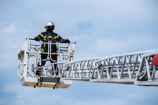Des pompiers sur une grande &eacute;chelle et un ciel bleu avec des nuages
