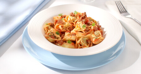 tortelloni with bolognese sauce. classic Italian pasta with spinach and ricotta in tomato-meat sauce. dish of mediterranean cuisine on a light background. food on the table on a sunny day.