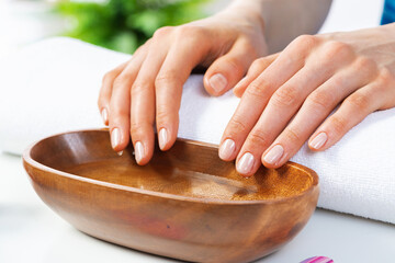Closeup female hands in wooden bowl with water