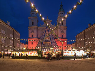 Salzburg, Austria. Christmas market at the Domplatz (Cathedral Square) in front of Salzburg Cathedral in twilight. The origins of the Salzburg Christmas market go back to the late 15th century.