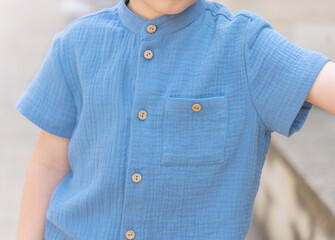 cute kid preschooler boy in casual blue color suit from muslin textile outside in parc posing for...