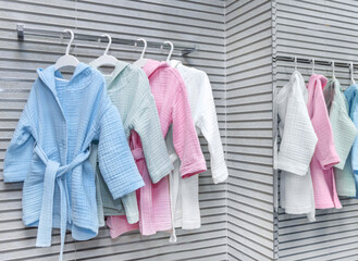 cute boy baby toddler kid in bathrobe in modern bathroom interior in front of sink.product clothes photo, smiling child in shower.different colors bathrobe on hangers.towel with hood - obrazy, fototapety, plakaty