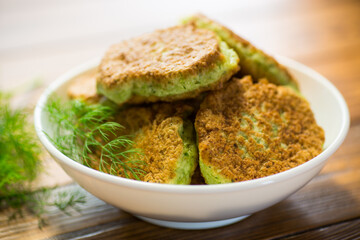 fried zucchini pancakes with herbs, in a plate .