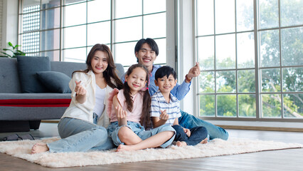 Asian happy cheerful joyful family husband and wife lover couple sitting on carpet floor with...