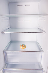 Open empty refrigerator with one donut on the shelf, diet concept