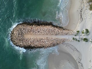 Aerial shot of a beach, featuring rocks and crystal-clear blue water