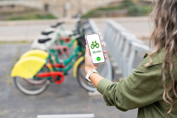 Woman renting a bicycle with her smartphone in the city