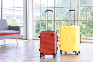 Two trolley color red and yellow luggage for traveling vacation road trip, summer vacation concept, traveler suitcases, living room interior with large windows, focus on suitcases