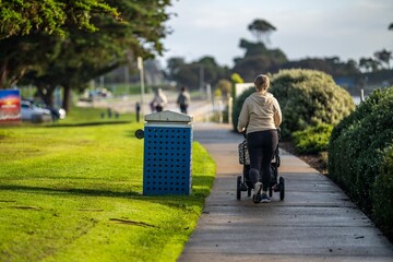 mother pushing a pram on a path by the ocean. young parent getting fit