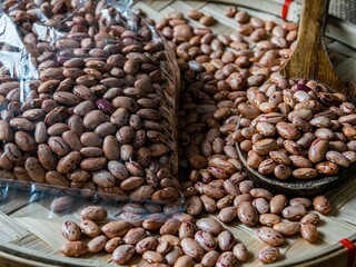 Obraz premium Closeup shot of a pile of pinto beans and a bag of pinto beans on a wooden platter