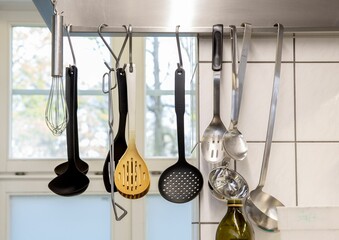 Row of decorative spats suspended from the ceiling in a kitchen setting.