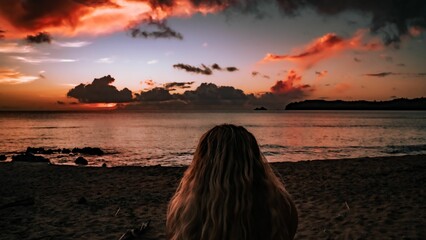 Fototapeta premium Young woman standing in the sand of a beach, with her back to the camera, Guam