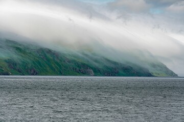 Dramatic landscape of Umnak, Alaska featuring a sky filled with billowing clouds