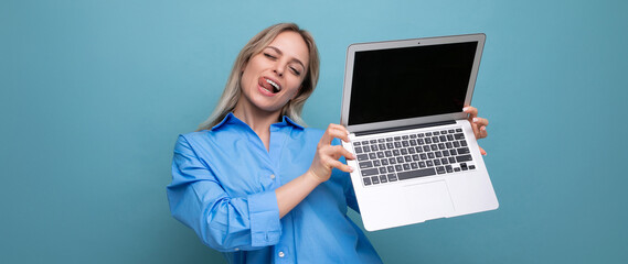 photo of adorable cute blond girl showing open laptop with empty space for website on blue background
