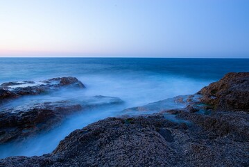 Idyllic long exposure shot of a rugged shoreline with tranquil aqua-blue waters - Powered by Adobe