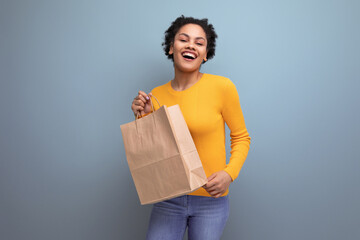 pretty young brunette latin female adult in yellow sweater uses recycled paper bag