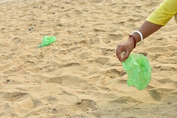 Fototapeta na wymiar Hand grabs a plastic bag blown onto the beach sand by the wind, a pollution concept.