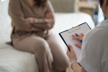 caring psychologist listens empathetically to her patient during a therapy session. She takes detailed notes, providing emotional support and guidance to help her patient overcome personal challenges