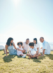 Parent, children and generations are relaxing on grass in summer for quality time on holiday in...