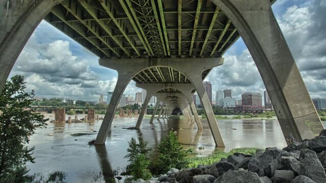 Timelapse of the river flowing under a bridge with the buildings of the city in the background