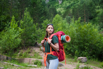 Young female tourist with backpack walking in forest