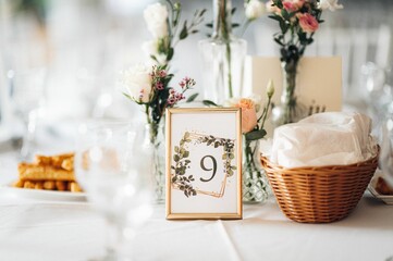 Fototapeta na wymiar Wedding table decorations with flowers and a frame with the number 9 on it.