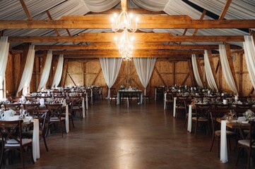 Cheerful wedding reception taking place in a rustic barn setting. © George Minciuna/Wirestock Creators
