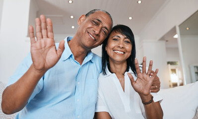 Video call, wave and a senior couple on a sofa in the living room of their home together for communication during retirement. Portrait, smile and a happy mature man with his wife on a virtual chat