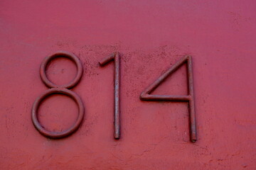 Numéro 814. Chiffres métalliques sur mur peint en vieux rose.