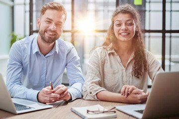 Attractive man and charming woman is pointing at the laptop screen, laughing together, resting