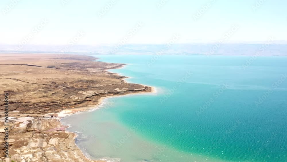 Poster beautiful footage over sandy beach by tranquil dead sea with bright sky on the horizon