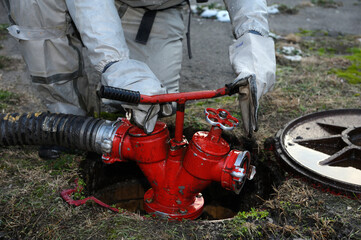 Rescuer hands in protective gloves turning valve of fire hydrant to water plant territory