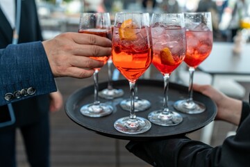 Man taking a glass of Aperol from a silver tray with glasses of beverage