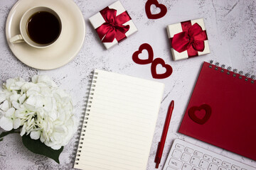 Red concept of working items with coffee, notebook and gift boxes on marble table.