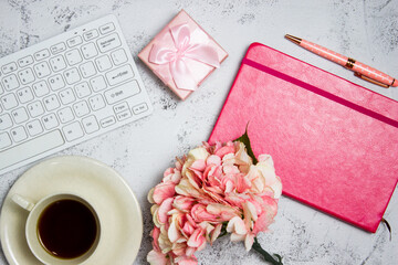 Working space and pink them with keyboard, flower, notebook over the grey background.