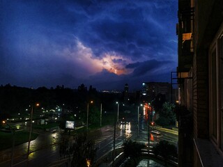 Nighttime urban skyline illuminated by a powerful lightning bolt striking the sky