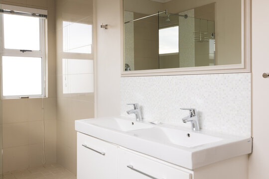 General view of bright bathroom with shower, mirror and washbasin