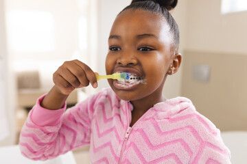 African american girl brushing teeth in bathroom