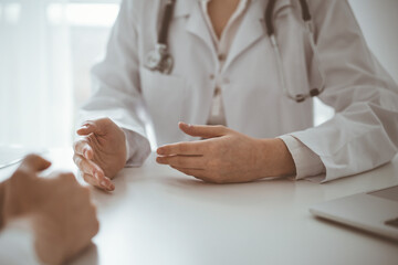 Doctor and patient discussing current health examination while sitting at the desk in clinic office, closeup. Medicine concept