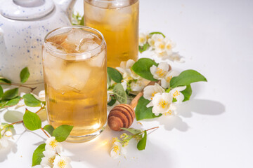 Organic herbal health summer cold drink. Jasmine flowers green tea, in glass, with ice cubes,...