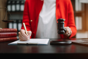 Justice and law concept. Female judge in a courtroom the gavel, working with digital tablet computer on wood table in sun light.