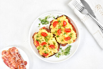 Scrambled eggs with microgreen and tomatoes on bread