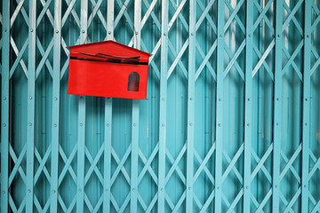 Red mail box install on the iron door. Document or paper information transfer concept. Classic object in digital transformation age.