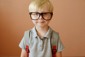 a blond schoolboy in glasses and with a backpack