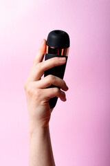 Female hand is holding black vacuum clitoral stimulator on a pink background. Place for text. Sex shop concept. Copy space