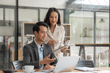 Businessman executive manager ceo talking to female coworker, using laptop and tablet discussing business plan at board room meeting