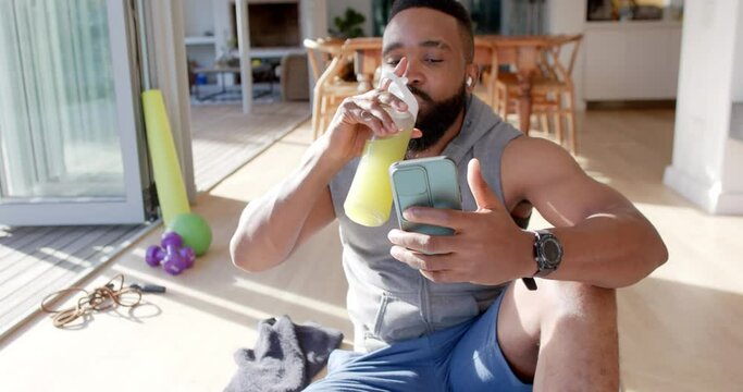 Happy african american man resting making video call using smartphone at sunny home, slow motion