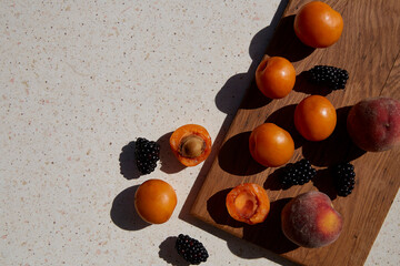 Close up of fresh healthy summer fruits, apricots and blackberry under hard shadows. Summertime. Copy space.