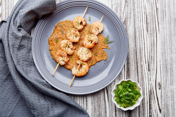 Catering seafood snacks. Grilled prawns on skewers on the sauce. Seafood barbecue, roast shrimps top view. Mediterranean recipe